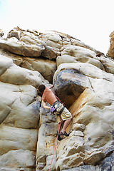 Image showing Man, mountain and rock climbing or chalk for grip as outdoor performance, adventure or gear. Male person, hanging and rope on cliff or fearless danger on boulder stone, training for exercise discover