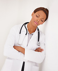Image showing Tired black woman, doctor and sleeping on wall in fatigue, burnout or stress at hospital. Face of exhausted African female person, surgeon or medical nurse asleep or overworked on job at clinic