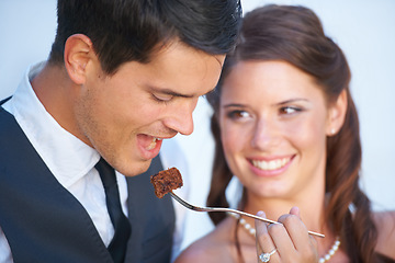 Image showing Smile, wedding and couple eating cake together for celebration of love together at party. Happy, cute and young bride feed husband sweet dessert at romantic marriage ceremony or event with commitment