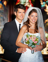 Image showing Happy couple, wedding and bouquet of flowers at church for marriage, love or commitment at ceremony. Married man and woman smile with floral roses and bridal dress for relationship or celebration