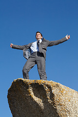 Image showing Businessman, success and freedom on cliff with sky, rock and peak of mountain in nature. Happy, person and celebration of winning an achievement, challenge or climbing in business and career progress