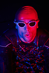 Image showing authentic triathlete swimmer having a break during hard training on night neon gel light