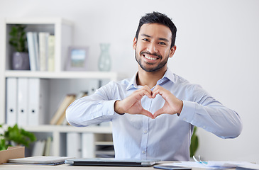 Image showing Asian man, heart hands and portrait with happy in office, job growth and consultant with trust sign. Professional person, care emoji and smile face, start up and business support by desk with laptop