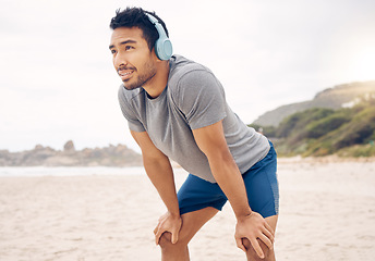 Image showing Fitness, headphones and portrait of man on beach running for race, marathon or competition training. Sports, workout and young male athlete listen to music, radio or playlist for exercise by ocean.