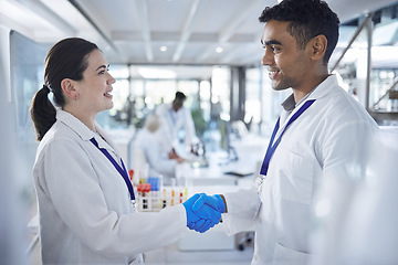 Image showing Science, handshake and man with woman in laboratory for agreement, deal or onboarding. Teamwork, medical research and scientist shaking hands in partnership, collaboration or introduction for doctors