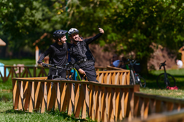 Image showing A blissful couple, adorned in professional cycling gear, enjoys a romantic bicycle ride through a park, surrounded by modern natural attractions, radiating love and happiness