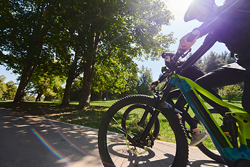 Image showing A blissful couple, adorned in professional cycling gear, enjoys a romantic bicycle ride through a park, surrounded by modern natural attractions, radiating love and happiness