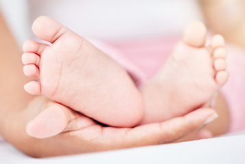 Image showing Family, care and the feet of a baby in the hands of a parent closeup in the bedroom of their home together. Kids, love or wellness and an infant child on a bed in an apartment with an adult person