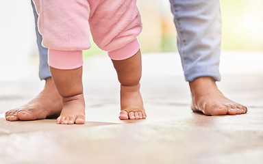 Image showing Walking, learning and feet of parent and baby on floor for child development, growth and first steps at home. Family, childhood and closeup of toddler for bonding, relationship and balance in nursery