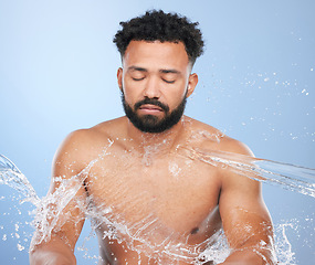 Image showing Skincare, water splash and man in studio for cleaning, hygiene or cosmetic care on blue background. Shower, face and topless male model relax with luxury hydration, pamper or bathroom beauty routine