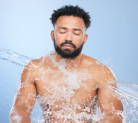 Image showing Black man, water splash and skincare for hygiene, cleaning or grooming against a blue studio background. Face of African male person, model and aqua for body hydration, shower or washing skin