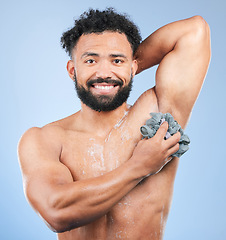 Image showing Shower, washing and portrait of man with sponge for cleaning, soap hygiene and skincare on blue background. Dermatology, bathroom and person with splash, foam and cosmetics for wellness in studio
