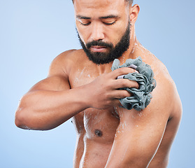 Image showing Shower, washing and man with sponge in studio for cleaning, hygiene and skincare on blue background. Dermatology, bathroom and person with soap, drops and cosmetics for wellness, health or self care