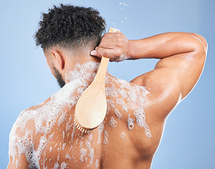 Image showing Shower, washing and man with brush and soap in studio for cleaning, hygiene and skincare on blue background. Dermatology, bathroom and person with foam and cosmetics for wellness, health or self care