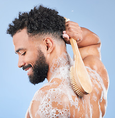 Image showing Shower, brush and man in studio for back cleaning, exfoliate or wellness on blue background. Soap, cosmetics and profile of happy model with body scrubber in a bathroom for hygiene, washing or care