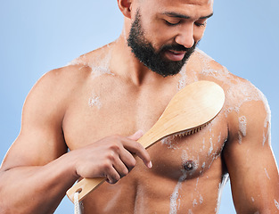 Image showing Man, shower and brush for cleaning in studio with armpit, scrub and thinking for hygiene by blue background. Person, guy and foam for spa, cosmetics and wellness for body, skincare and healthy