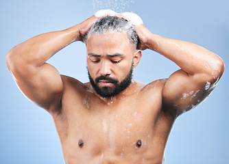 Image showing Shower, washing hair and man with water in studio for cleaning, hygiene and skincare on blue background. Dermatology, bathroom and person with shampoo, foam and grooming for wellness and health