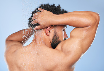Image showing Man, shower back and splash in studio with water, wash or hygiene with self care by blue background. Person, guy and muscle with hair, wellness or health for skin, natural dermatology and body