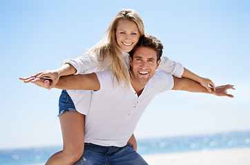 Image showing Couple, beach and happy for piggy back in portrait, vacation or freedom in summer sunshine for bonding. Man, woman and plane game with smile, care or love by sand, waves or play on holiday in Napoli