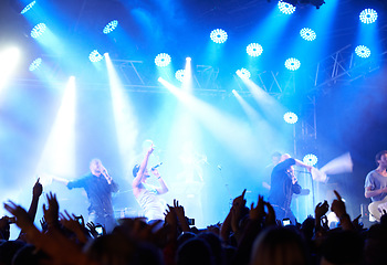 Image showing Concert crowd, music festival lights or band audience listen rock, metal or celebrity star, artist or stage performance. Night show energy, excited group celebrate and fans cheers for musician singer