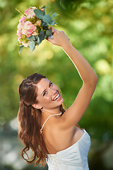 Image showing Woman, throwing and wedding rose bouquet with love, commitment and trust ceremony for marriage. Engagement, celebration and flowers for event in a park with a red floral plant and bride dress outdoor