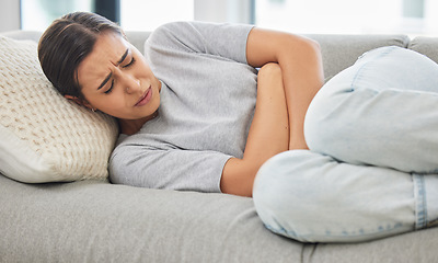 Image showing Woman, stomach pain and stress on sofa, sick or menstruation with anxiety, gas or virus in home living room. Girl, abdomen and emergency for gut health, constipation or cramp on lounge couch in house