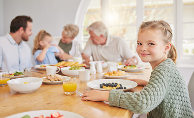 Image showing Girl child, portrait and breakfast with family, smile and morning in home with diet, nutrition or eating. Kid, plate and happy for fruit, juice and relax in home dining room, parents and grandparents