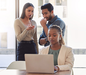 Image showing Office bully, woman and working at laptop with coworkers talking in a corporate workplace with gossip. Young black person typing on a computer with internet and joke with staff being mean at desk