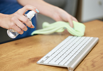 Image showing Hands, keyboard and spray bottle with a person cleaning a keyboard on a wooden desk for hygiene. Technology, health and sanitize with an adult wiping a wireless or bluetooth device on a table