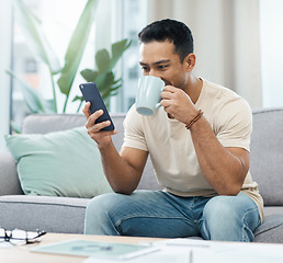 Image showing Man, phone and reading with coffee on sofa in home for taste of hot beverage. Asian person, texting and mobile app for message, internet and social media by cellular with drink to relax living room