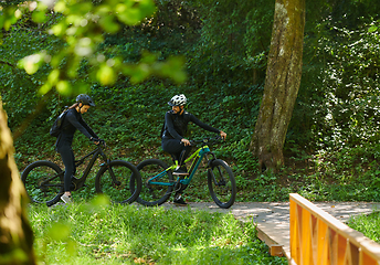 Image showing A blissful couple, adorned in professional cycling gear, enjoys a romantic bicycle ride through a park, surrounded by modern natural attractions, radiating love and happiness