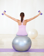 Image showing Woman, back and exercise on ball, dumbbells and balance in gym, training and strong muscle in arms. Girl, workout and fitness with pilates, weightlifting and hard work for health, wellness and body