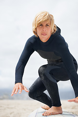 Image showing Portrait, beach and a man surfing instructor on sand, teaching balance, skill or technique. Fitness, summer and a young person in a wetsuit on a surfboard as a sports coach on the coast in Australia