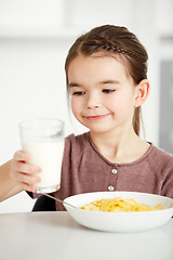 Image showing Happy girl, milk and cereal for breakfast morning, calcium or natural nutrition in kitchen at home. Young female person, child or kid with glass of cream for food, meal or snack in health or wellness