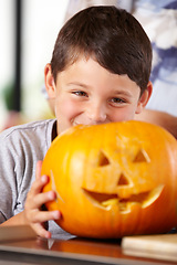 Image showing Face, halloween, and pumpkin with a boy in the kitchen of his home for holiday celebration or tradition. Smile, scary and carving with a young child closeup in his apartment for vegetable decoration