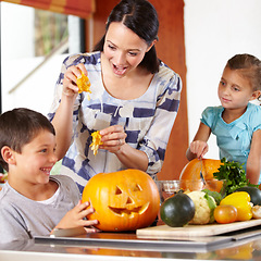 Image showing Mother, girl and boy with pumpkins for halloween in the kitchen of their home for holiday celebration. Family, food or tradition and a woman teaching her young children how to carve vegetables