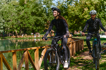 Image showing A blissful couple, adorned in professional cycling gear, enjoys a romantic bicycle ride through a park, surrounded by modern natural attractions, radiating love and happiness