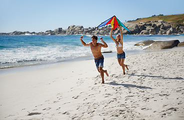 Image showing Couple, running and happy with kite, beach and summer sunshine for vacation, freedom or play in air. Man, woman and happy to launch wind toys, bonding or holiday by sea for adventure in Naples, Italy