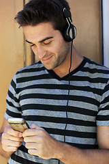 Image showing Cellphone, happy and man with headphones in city for listening to music, audio and radio. Fashion, smile and person online for streaming subscription, song and playlist on holiday, vacation and relax