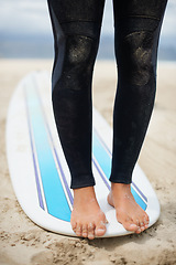 Image showing Feet, balance and surfboard with a person on the beach for fitness, recreation or sports training closeup. Legs, sand and nature with an athlete surfing outdoor on the coast for exercise or health