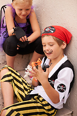 Image showing Siblings, playing and halloween costume by outdoor stairs, toys and happiness in childhood. Boy, girl and smile face for holiday with finger puppet games, theme clothes fairy and pirate in backyard