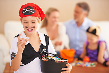 Image showing Happy boy, candy and halloween in home, face paint and happiness in childhood. Son, chocolates and family on holiday event with sweets, pirate costume and love care with celebration together in house