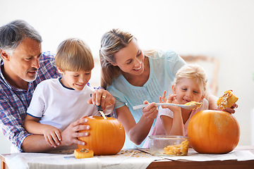 Image showing Family, halloween and carving a pumpkin with children in a home for fun and bonding. Man and woman or parents and young kids together for creativity, holiday lantern and happy craft at a table
