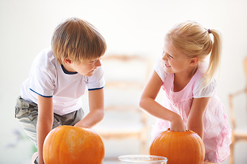 Image showing Halloween, happy and carving a pumpkin with children at a home table for fun and bonding. Boy and girl or young kids as siblings together for creativity, holiday lantern and craft and play in a house