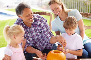 Image showing Halloween, family and carving a pumpkin with children outdoor in home backyard for fun and bonding. Man and woman or parents and young kids together for creativity, holiday lantern and happy craft