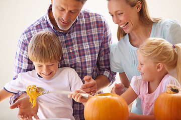 Image showing Halloween, family fun and carving a pumpkin with children in a home for bonding and helping with craft. Man and woman or parents and young kids together for creativity, holiday lantern and happy