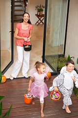 Image showing Family home, halloween and children running with candy for fun, adventure or vacation tradition. Happy, love and mother watching excited kids in costume, laugh and playful energy for holiday prank