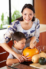 Image showing Halloween, pumpkin and a woman in the kitchen with her son for holiday celebration at home. Creative, smile or happy with a mother and boy child carving a face into a vegetable for decoration