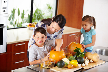 Image showing Mother, sister and brother with pumpkins for halloween in the kitchen of their home for holiday celebration. Family, food or tradition and a woman teaching her sibling kids how to carve vegetables