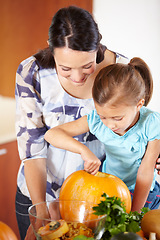 Image showing Halloween, pumpkin and a woman in the kitchen with her daughter holiday celebration at home. Creative, smile or happy with a mother and girl child carving a vegetable for decoration or tradition